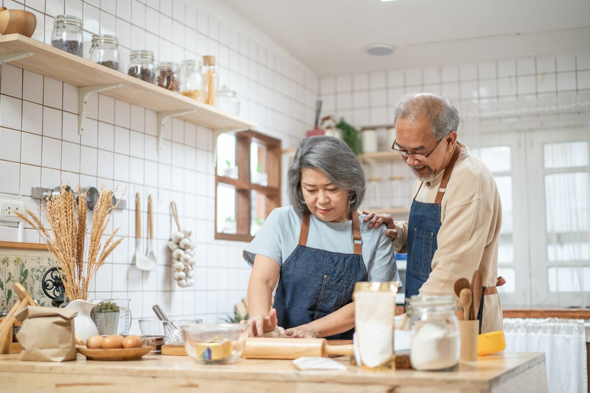 Asian Senior elderly couple standing in kitchen at house feeling happy and enjoy retirement life