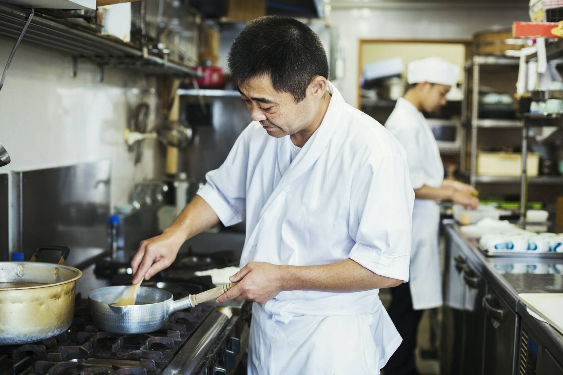Chef working in the kitchen of a Japanese sushi restaurant, cooking on stove.