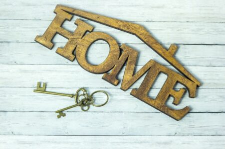 Concept of housing acquisition, the key and the word house on a wooden background